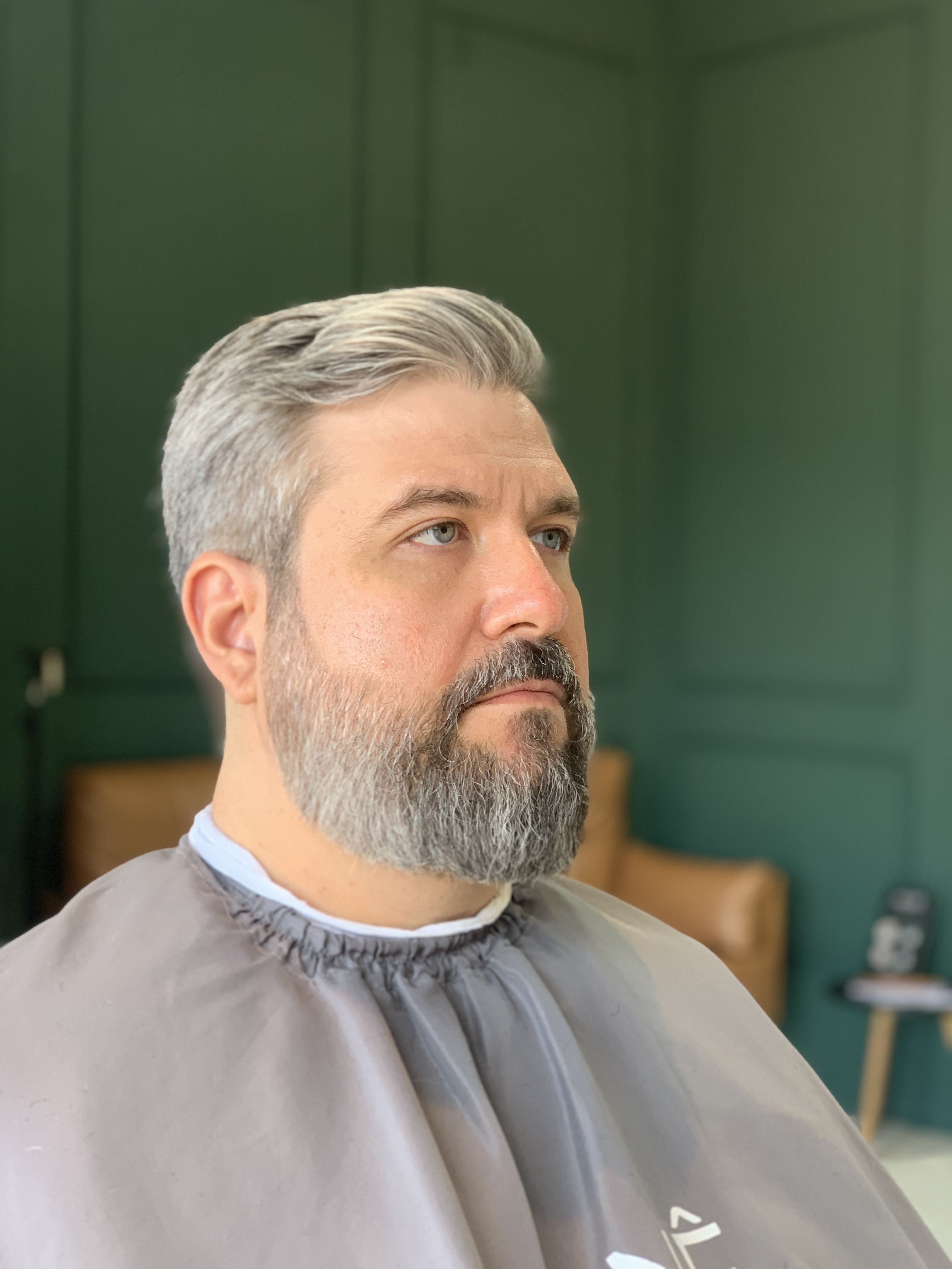 Cliente com cabelo e barba grisalhos após atendimento na MUNÊ Barbearia